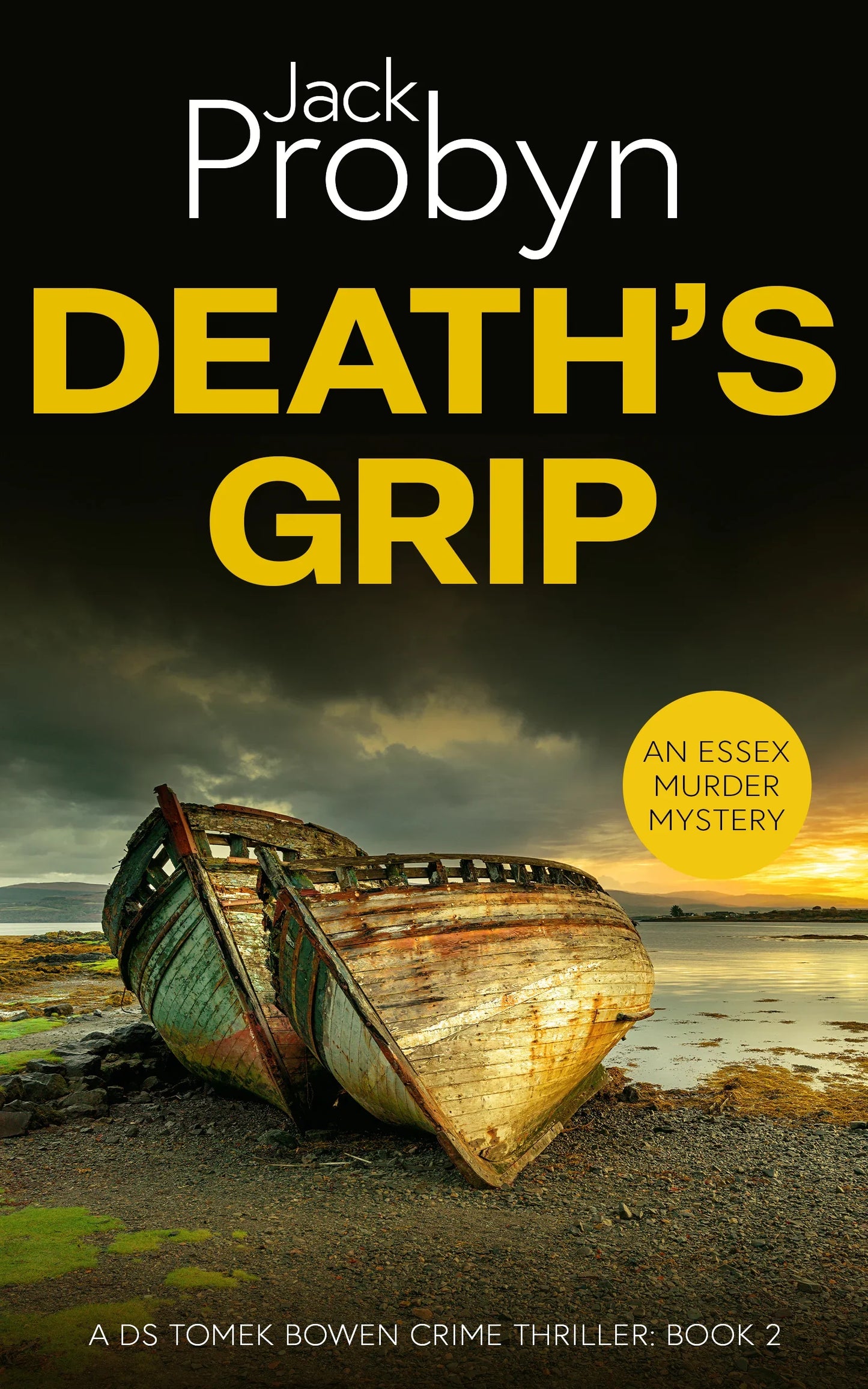 Book cover of Death’s Grip, an Essex Murder Mystery by Jack Probyn. A gritty crime thriller featuring two decaying, rusted boat hulls abandoned on a rocky shoreline at sunset. Book 2 in the DS Tomek Bowen series, perfect for fans of JD Kirk and JM Dalgliesh